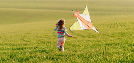 Little girl holding kite at sunsetの写真素材