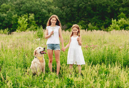 Sisters with dog on flowering meadowの写真素材