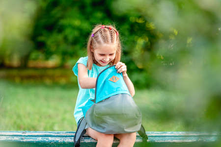 Schoolgirl peeking into backpack in parkの写真素材