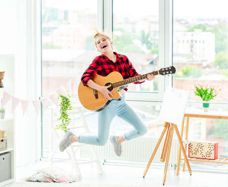 Happy teenage girl jumping with guitar