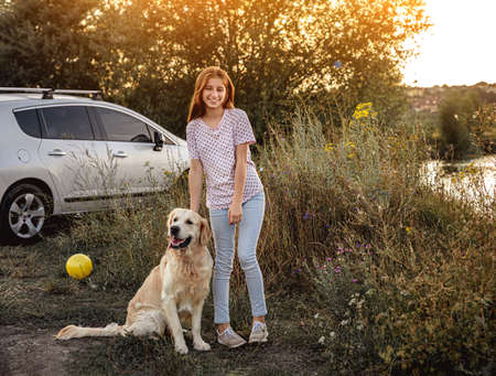 Young girl with dog near carの写真素材