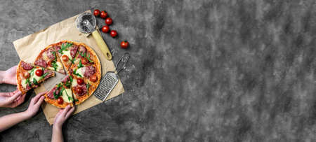 childrens hands take homemade pizza with salamiの写真素材