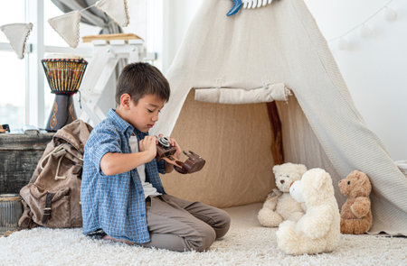 Little boy taking picture of plush teddyの販売画像