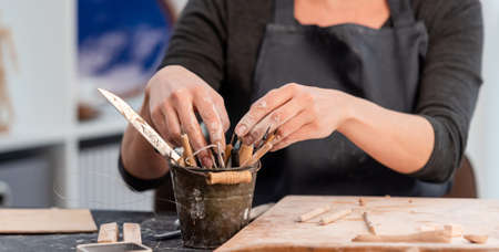 Woman potter taking out tools from bucket