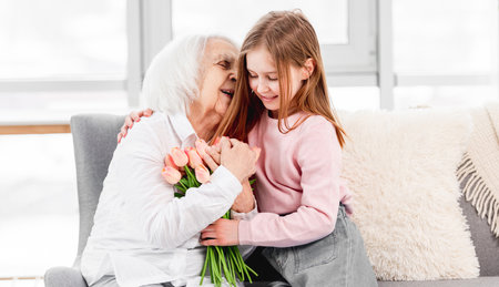 Grandaughter gives flowers to grandmotherの写真素材
