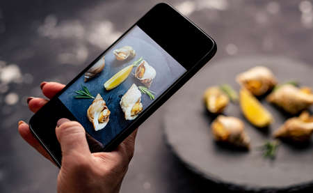 Snails with lemon on black platterの写真素材