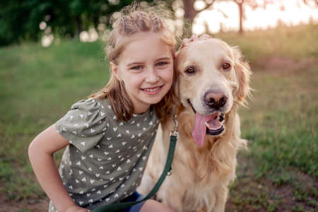 Preteen girl with golden retriever dog outdoorsの写真素材