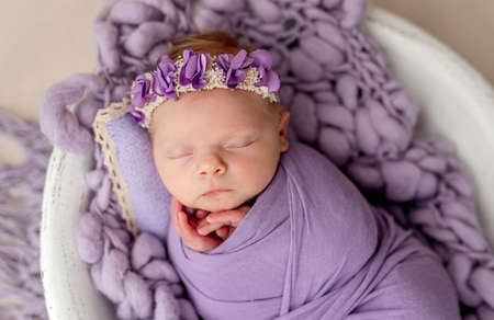 Newborn sleeping wrapped in violet blanketの写真素材
