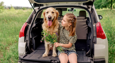 Preteen girl with golden retriever dog in the carの写真素材