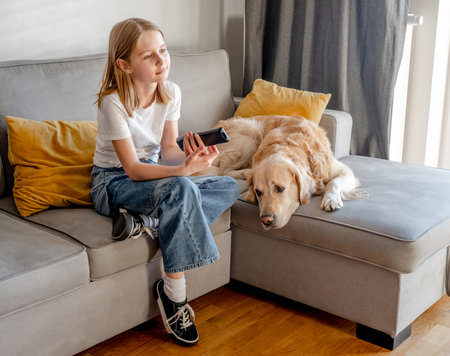 Preteen girl with golden retriever at homeの写真素材