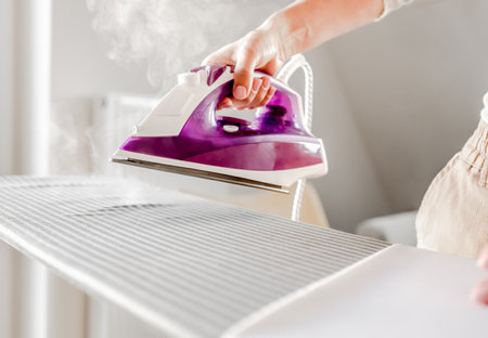 Girl hand using iron for wrinkled clothesの写真素材