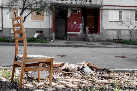 Abandoned chair and ruins near destroyed residential building with rockets during Russian war in Ukraine. Terrorist military agression in Kharkivの写真素材