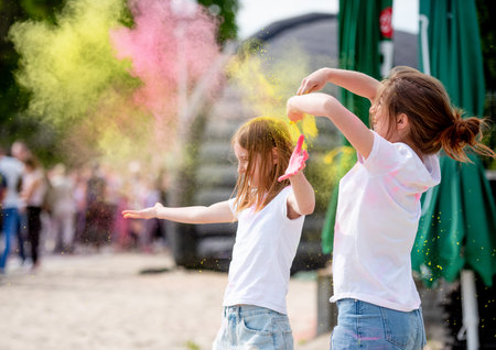 Pretty sisters in indian traditional Holi festival with colorful powder having fun. Female teenager and preteen child friends enjoying holidayの写真素材