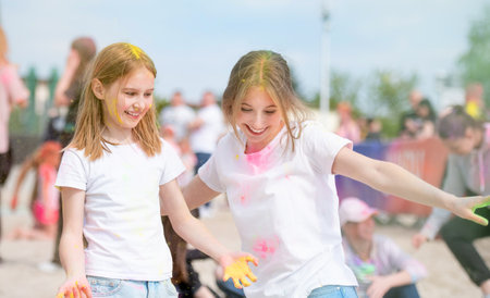 Pretty girls sisters in indian traditional Holi festival with colorful powder smiling. Female teenager and preteen child friends enjoying holidayの写真素材