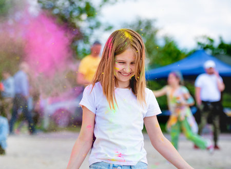Preteen girl in indian traditional Holi festival with colorful powder having fun. Female child kid enjoying positive holiday of Indiaの写真素材
