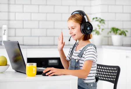 Preteen girl wearing headphones study with laptop. during online lesson at home at pandemic coronavirus.の写真素材