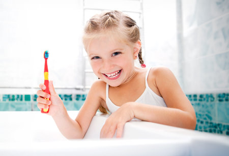 Little girl brushing teeth in bathの写真素材