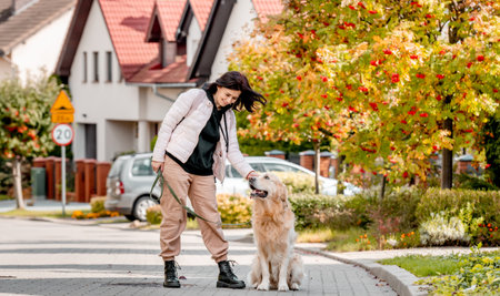 Preteen girl in pink jacket with golden retriever dog smiling at street. Pretty child kid with pet doggy labrador spend autumn time outdoorsの写真素材