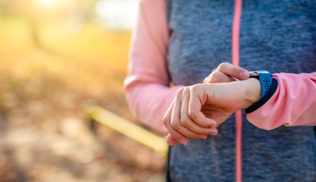 Girl with smart fitness watch during workout outdoors at autumn time. Young woman with sport technology gadgetの写真素材