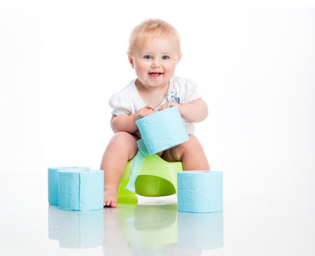 little baby sitting on a pot and keeps the toilet paper. studio photo on white backgroundの写真素材