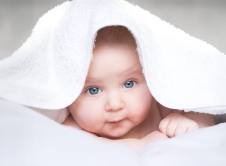 baby girl is under the white blanketの写真素材