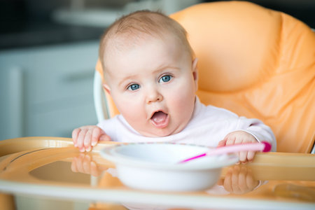 smiley baby girl is holding a spoon in his mouth and going to eatの写真素材
