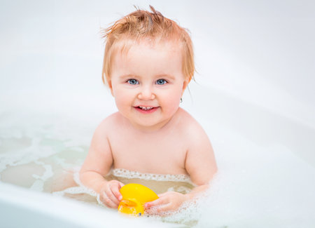 happy 1 year-old girl bathes in a bath with a duckの写真素材