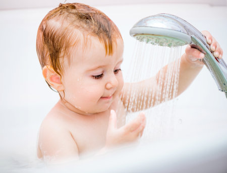 cute 1 year-old girl bathes in a showerの写真素材