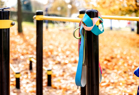 Exercise rubber bands for fitness hang on steel bar for workout in an autumn park. Outdoor sportsの写真素材