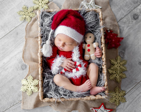Newborn baby boy wearing Santa Christmas costume sleeping in basket with xmas decoration. Little infant child New Year portraitの写真素材