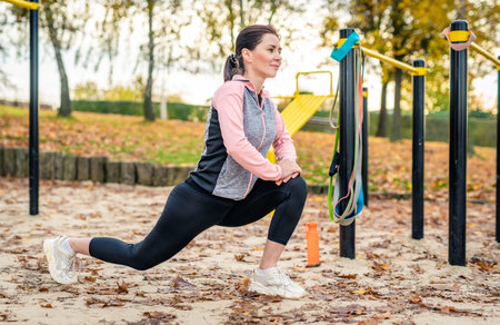 Fitness girl doing lunges outdoots in autumn time. Young woman exercising at nature in parkの写真素材