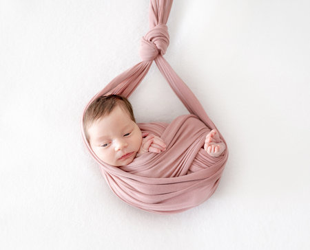Adorable newborn baby girl sleeping in hammock portrait. Cute infant child kid swaddled in fabric resting in swingの写真素材