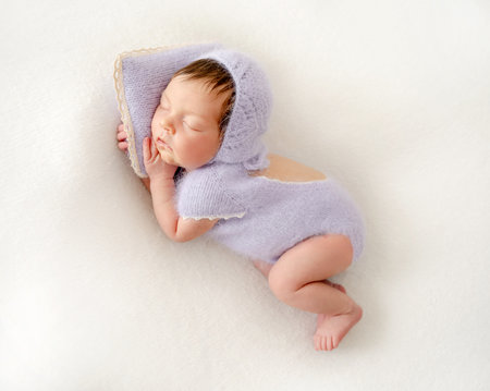 Adorable newborn baby girl sleeping on pillow. Cute infant child kid in knitted dress napping lying on tummyの写真素材