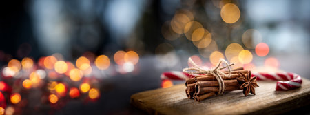Christmas cane candy beside cinnamon sticks and star anise on garland illumination backgroundの写真素材