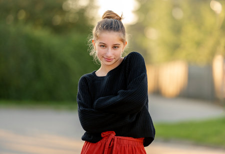 Beautiful teenager girl posing in park outdoors at nature. Pretty teen model in trendy clothes at street portraitの写真素材