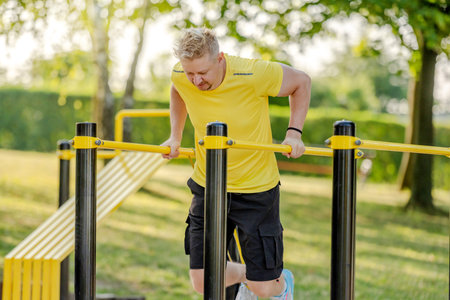 Man doing push ups with horizontal bar outdoors in park for healthy wellbeing and arm workout. Sportsman guy making strength training for muscleの写真素材