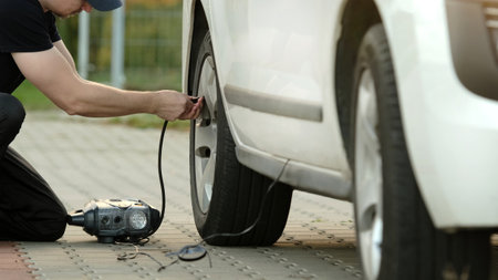 Man Lifts Car With Jack On Street As Driver Replaces Wheelの写真素材