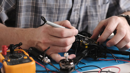 Repair Man Soldering Wires And Microchip Board On FPV Hobby Drone At Service Centerの写真素材