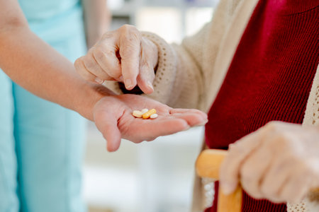 NurseS Hand Holds Pills That An Elderly Woman Takes From Her In A Close-Up Shotの写真素材