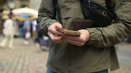 Man On Street Pulls Out Euro From Wallet And Counts Themの写真素材