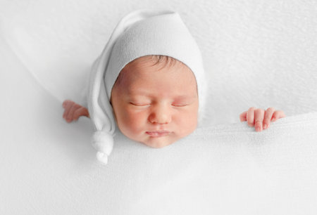 Newborn Girl Sleeps Under Blanket During Infant Photoshoot In Studioの写真素材