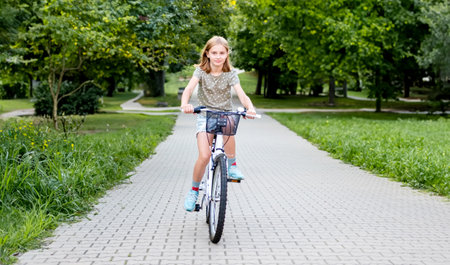Cute preteen girl riding bycicle outdoors and smiling in beautiful european city. Pretty child with bike at streetの写真素材