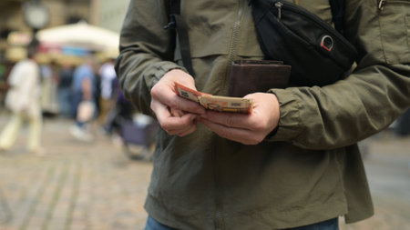 Man On Street Pulls Out Euro From Wallet And Counts Themの写真素材
