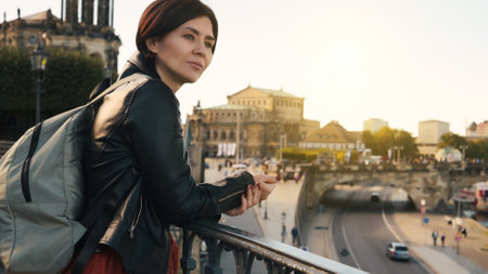 Young Woman Admires City View, With Blurred Cityscape In Autumn As Backdropの写真素材