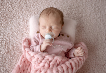 Baby Girl In Pink Outfit Sleeps With Pacifier During Newborn Photo Session In Studioの写真素材