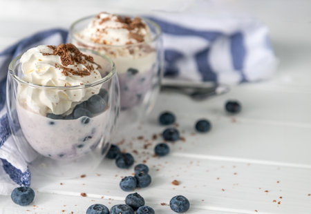 Dessert from yogurt with blueberries and chocolate on a white wooden backgroundの写真素材