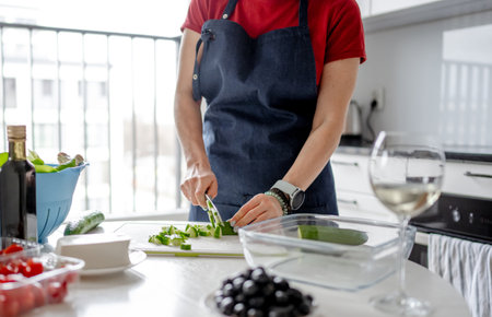 WomanS Hands Are Slicing Cucumber For Greek Salad With A Glass Of White Wine Nearbyの写真素材