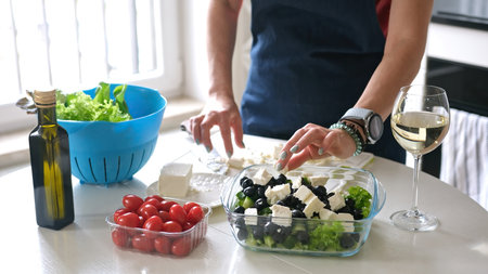 Housewife Puts Cheese In Bowl With Greek Salad Preparing Homemade Foodの写真素材