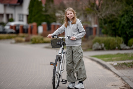 Girl Rides Bicycle Among Private Houses In Europe During Springの写真素材