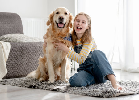 Girl With Golden Retriever Dog Poses At Home On Floor For A Portrait With Dogの写真素材
